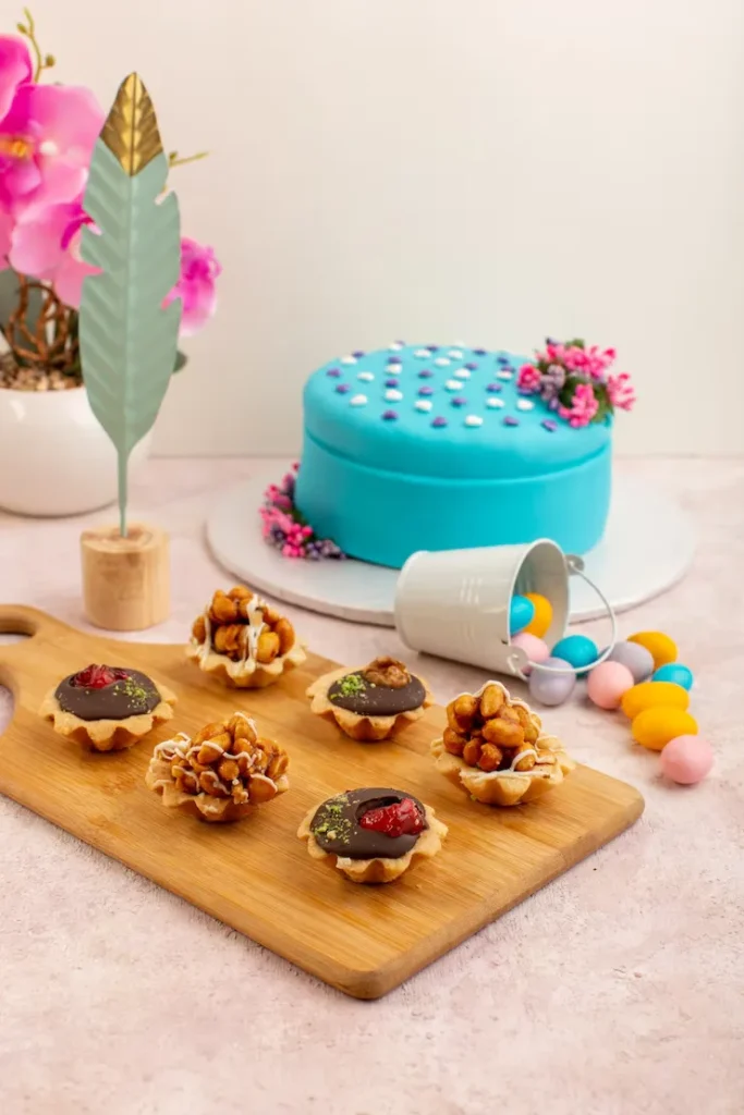 front-view-little-chocolate-cakes-with-candies-blue-birthday-cake-pink-desk_140725-25402